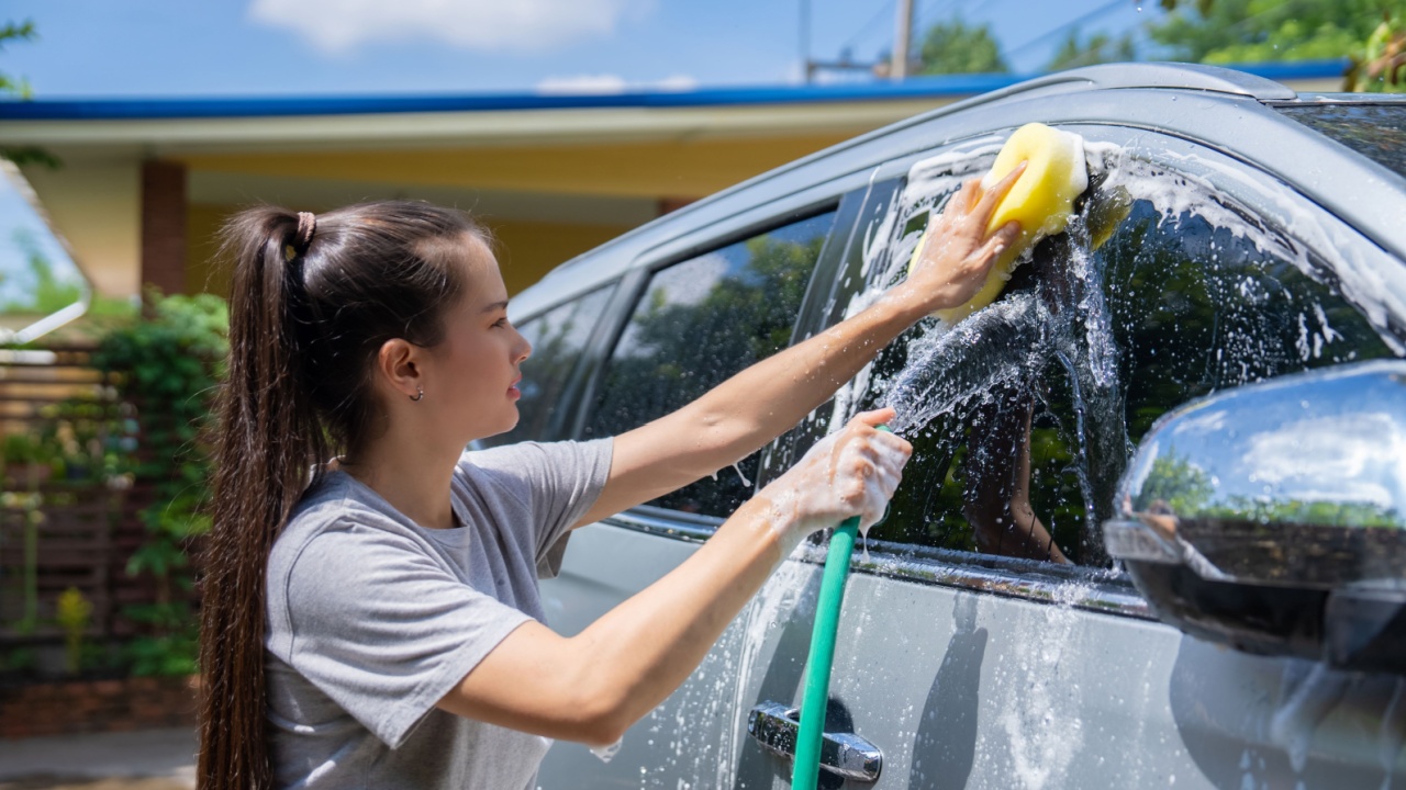 woman washing car with hose